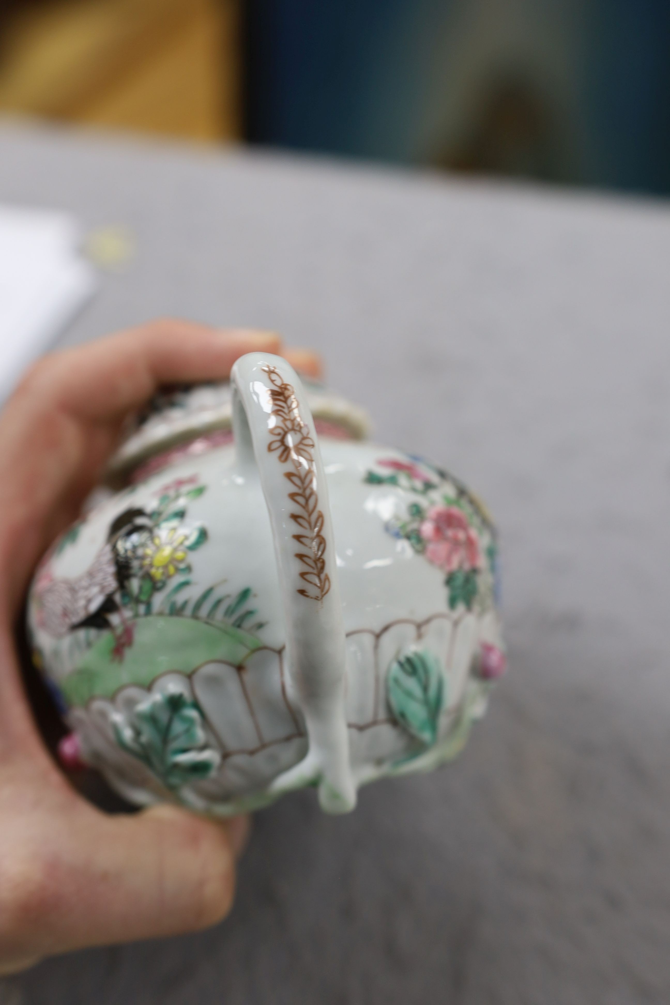 A Chinese famille rose chrysanthemum moulded teapot, early Qianlong period, painted with a cockerel amongst flowers, on a cage work base, 10 cms high